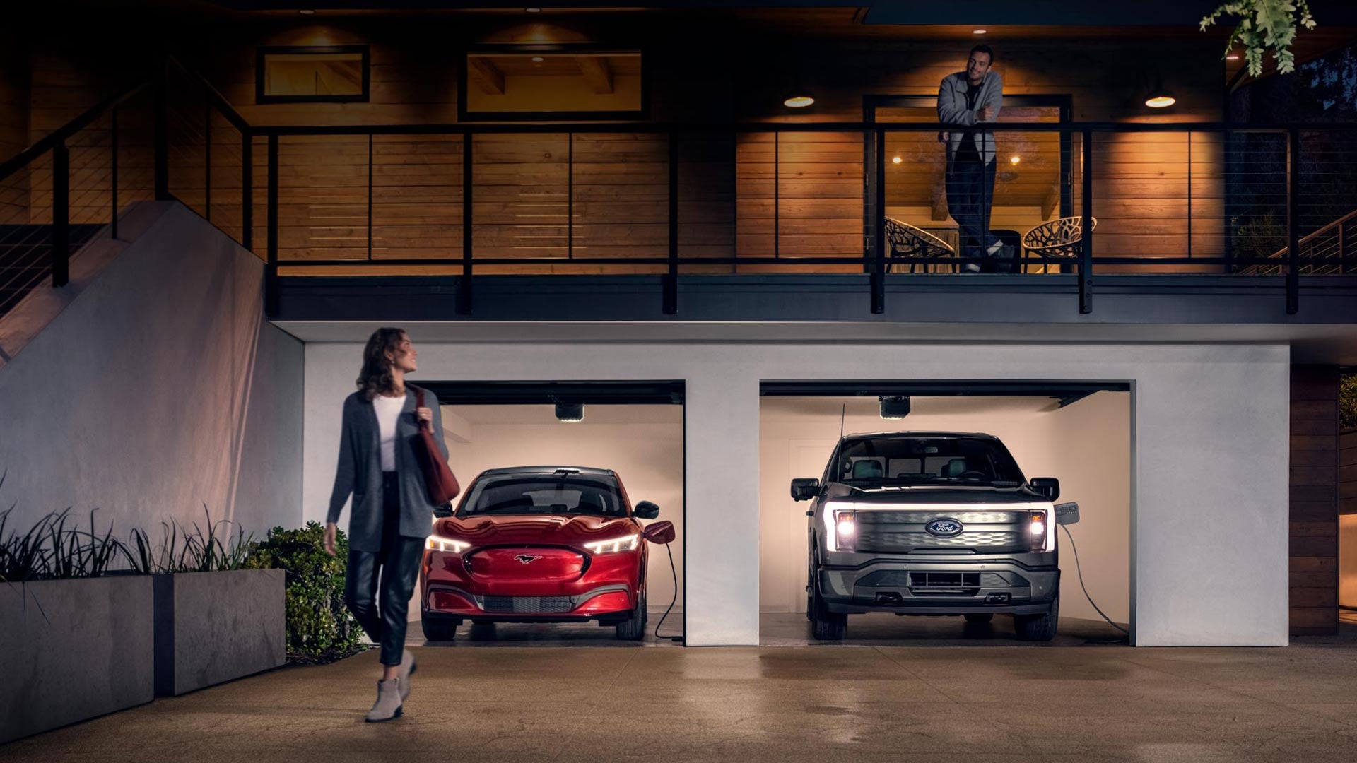 Woman walking out from home garage with a 2024 Mustang® Mach-E and Ford Lightning® truck in plugged-in and charging | Cavalier Ford Greenbrier in Chesapeake VA
